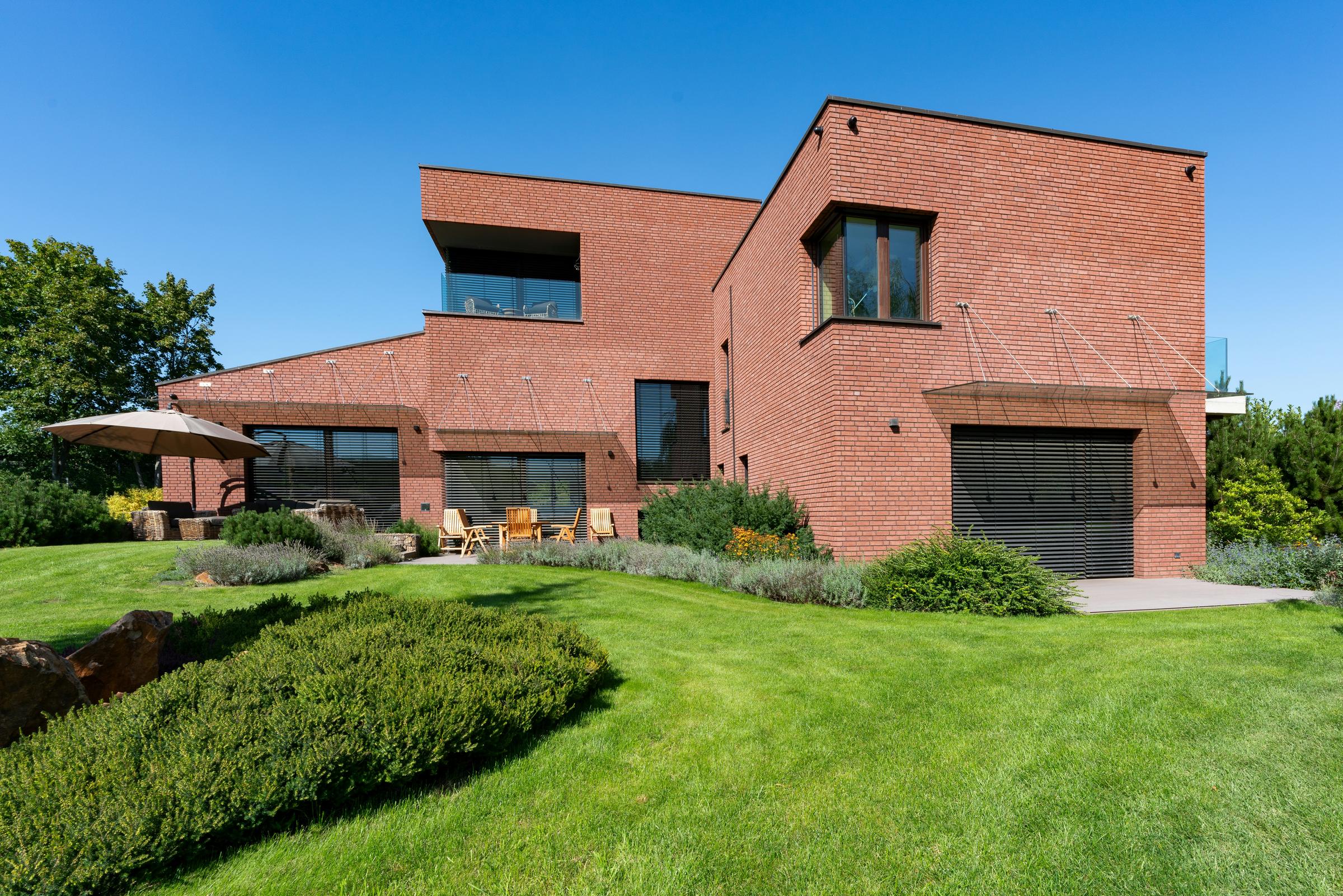 Modern brick villa with a large lawn and a sunny terrace